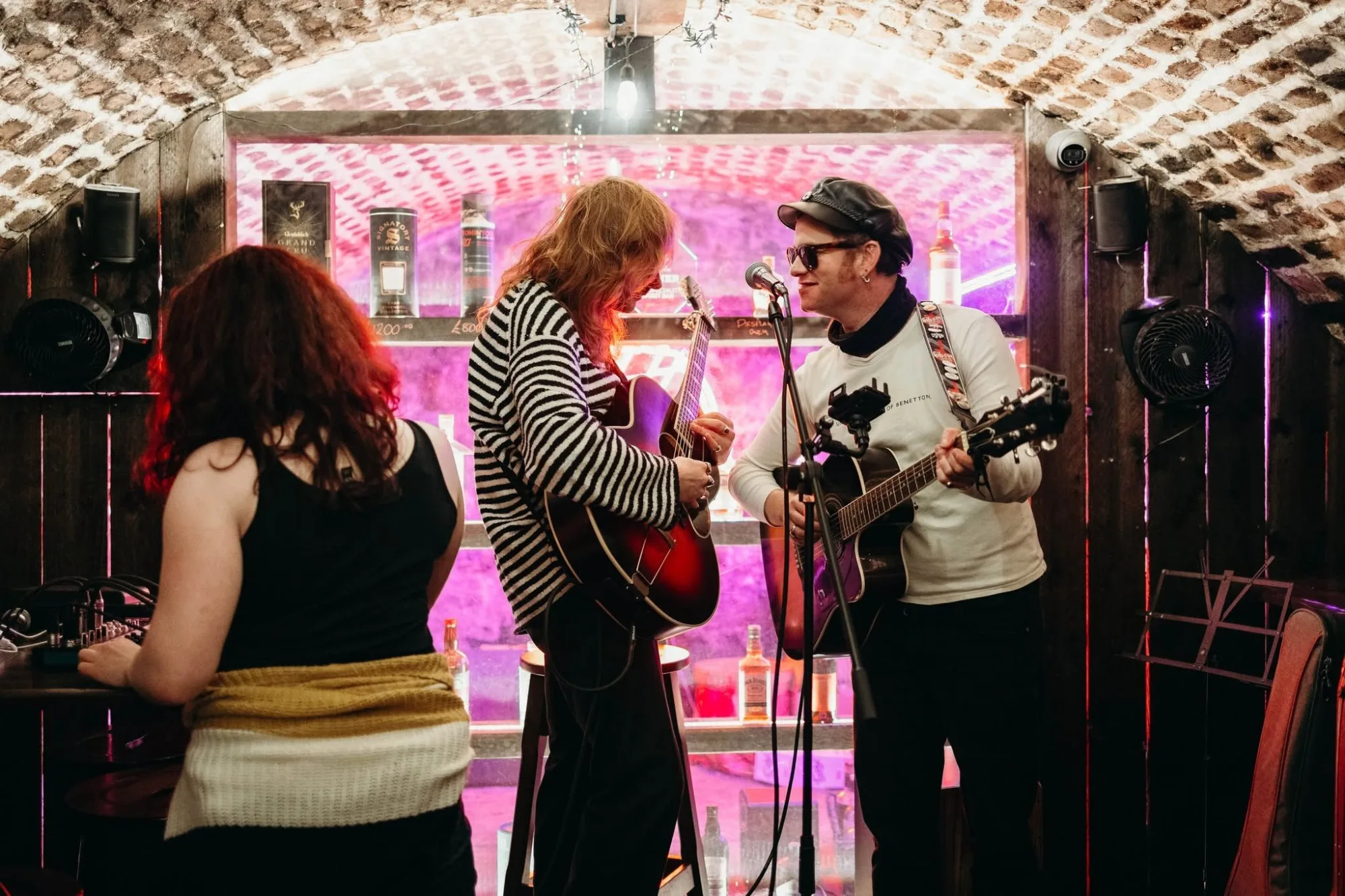 Musicians performing on a pink lit stage during live music night at The Old Workshop, Aberdeen